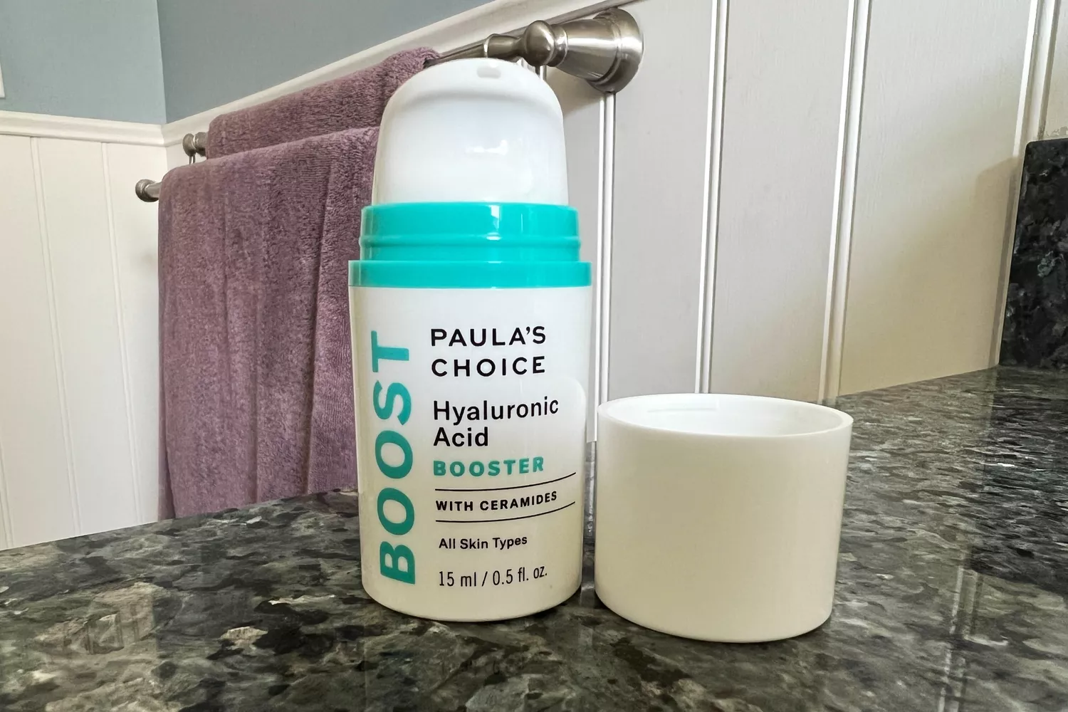 A bottle of Paulas Choice Hyaluronic Acid Booster with Ceramides on a bathroom counter